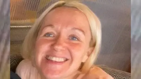 A woman with blonde hair smiles at the camera