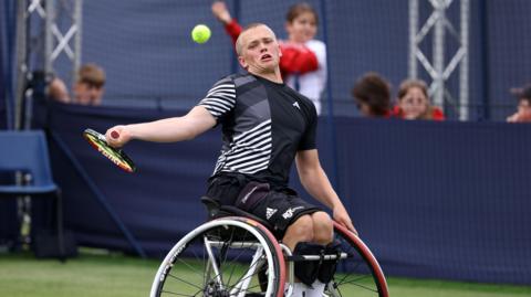 Ben Bartram stretching for a shot during a tennis match