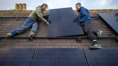 Getty Images Generic image of two installers putting solar panels on the roof of a property in Kent in 2025