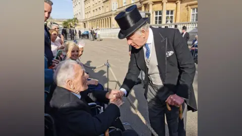 Family photo John Dennett pictured shaking hands with King Charles at Buckingham Palace