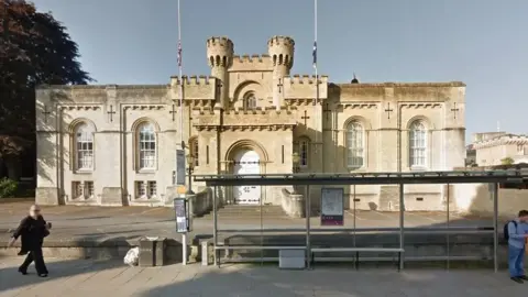 A Google Maps picture of Oxford Coroner's Court, a Grade II listed building. A bus stop stands in front of it.