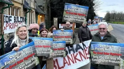 Ellis Karran / LDRS Protesters against the solar farm holding placards with slogans against the development