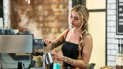 A young woman with long blond hair working in a coffee shop