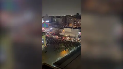 People protesting down a street at night.