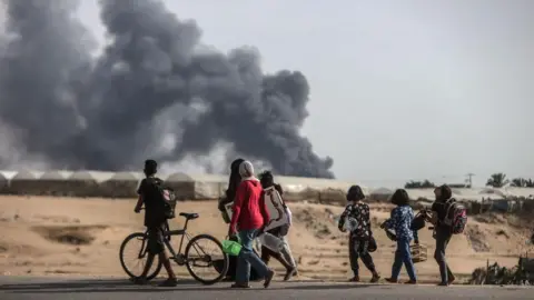 Anadolu Palestinians look at smoke as they flee the city of Rafah, in the southern Gaza Strip (28 May 2024)