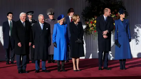PA Media King Charles III and Britain's Queen Camilla greets Germany's President Frank-Walter Steinmeier and his wife Elke Buedenbender. All wear heavy jackets standing on red carpet.