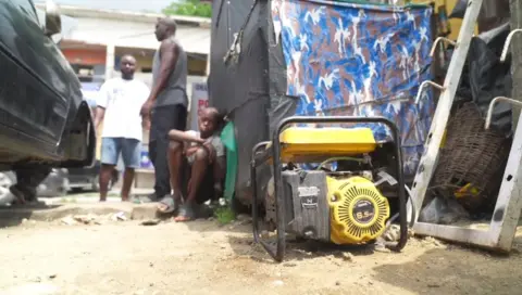 A generator is on the floor while there are children around