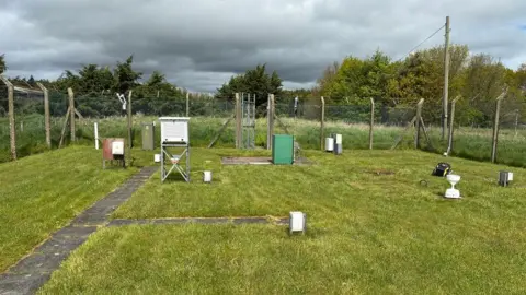 Met Office A fenced off area containing weather recording equipment surr
