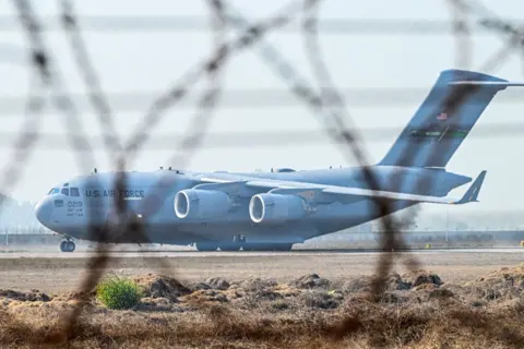 GETTY IMACTS Sebuah pesawat udara AS C-17 Globemaster III yang membawa migran India tidak berdokumen yang dideportasi oleh tanah AS di Bandara Internasional Sri Guru Ram Dass Jee di Amritsar, Punjab, India, pada hari Rabu, 5 Februari 2025.