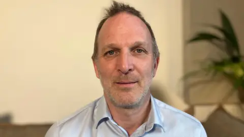 The head and shoulders of Dr Jack Hawkins, who is wearing a light blue shirt.