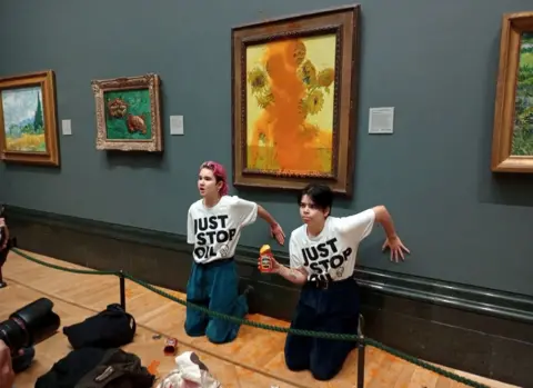 Just Stop Oil/Reuters Activists of "Just Stop Oil" glue their hands to the wall after throwing soup at a van Gogh's painting "Sunflowers" at the National Gallery