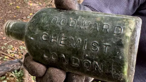 An old chemist's bottle. It has the words 'Woodward Chemist London' engraved on the side of it.