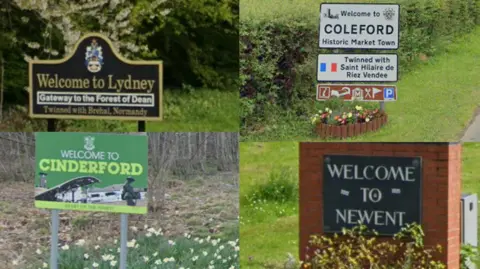 Google Four road signs of different sizes and styles - some traditional metal signs, another written on brick, welcome drivers to the four market towns in the Forest of Dean of Lydney, Coleford, Cinderford and Newent.