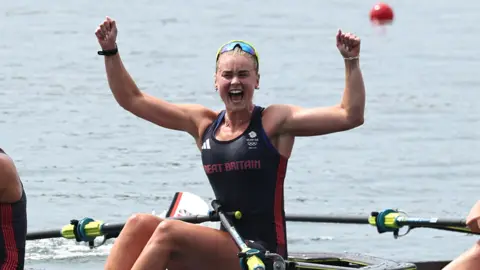 Getty Images/Francois Nel Hannah Scott celebrating with her arms in the air on a rowing boat. She is wearing a tank top with "Great Britain" written across the chest.