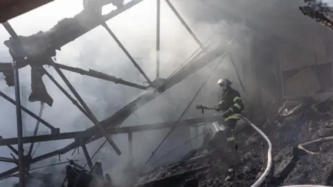 Getty Images Oekraïense hulpverleners blussen een fabrieksbrand na Russische beschietingen terwijl de Russisch-Oekraïense oorlog voortduurt in Kostantinivka, Oekraïne.