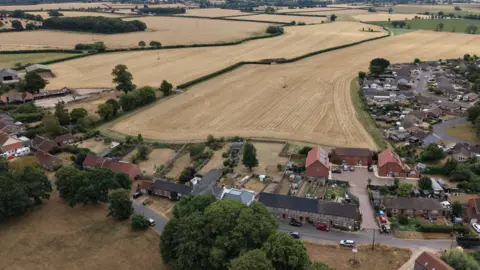 Shaun Whitmore/BBC An aerial image of a stubble field and surrounding houses 