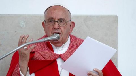 Pope Francis delivers a service. He is wearing a red robe.