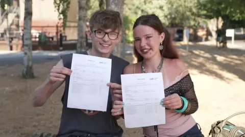 A man and a woman showing off their A-Level results.
