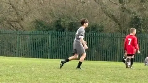 Supplied A young boy in a grassy field and grey sportswear running.