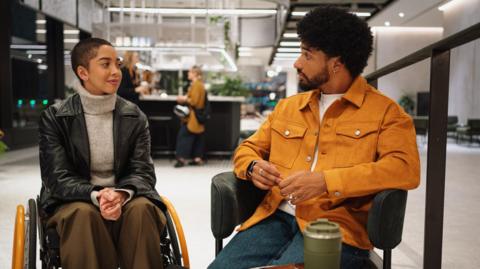 A woman in a wheelchair talks to a man