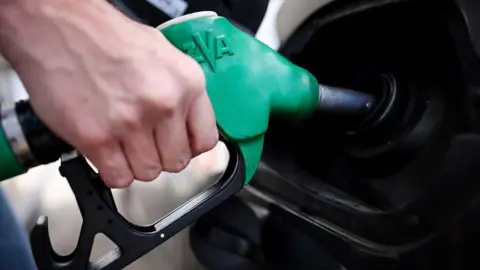 Close-up image of a green petrol pump refilling a car 