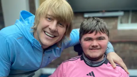 Claire House Paddy Pimblett, wearing a blue tracksuit top, meets Luke Hill, who is wearing a pink Adidas top