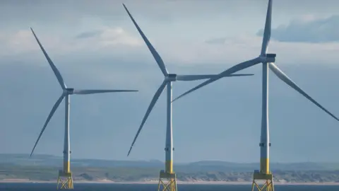 Getty image three offshore wind turbine away from Britain's coast in the sea