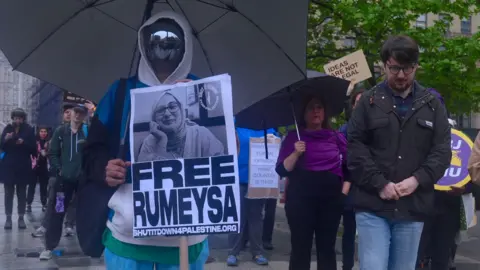 Someone holds a sign in protest with Rumeysa Ozturk's face