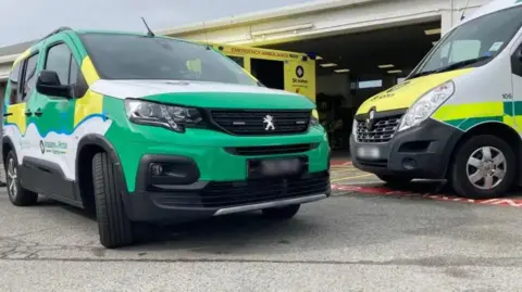 Two yellow, green and white St John Guernsey ambulance cars in front of its building.