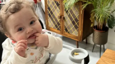 Police handout Baby Preston Davey has a finger in his mouth as he is eating in a high chair. He has brown curly hair and he is wearing a cream baby grow with an elephant on the front and a bib.