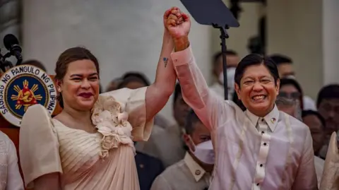 Getty Images Philippine Vice-President Sara Duterte raises the hand of President Ferdinand Bongbong Marcos.