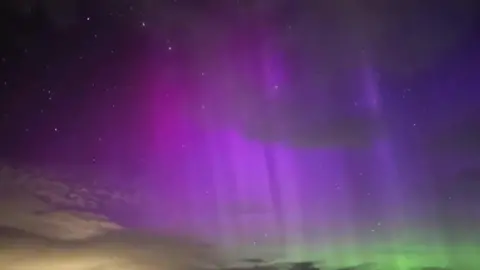 A purple, green, orange and dark night sky showing the Northern Lights.