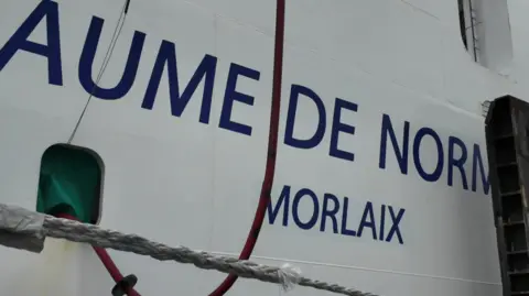 A large red cable is plugged into the side of the Guillaume de Normandie.