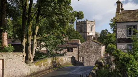 Getty Images The village of Kettlewell in the Yorkshire Dales featuring a small road surrounded by trees and stone buildings