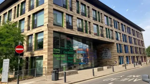 LDRS A modern building with different shades of brickwork has a large council crest by floor-to-ceiling glass windows