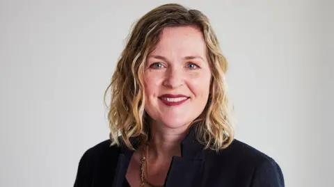 CIPD Headshot of Claire McCartney. She has blue eyes, wears red lipstick, and has shoulder-length blonde hair with brown roots