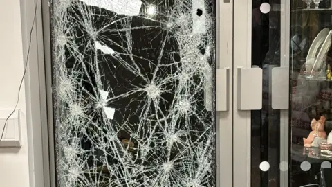 A close-up of a glass door that has been smashed repeatedly.