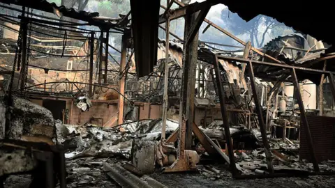 Charred remains of a home burned in the wildfires in the Madrid community. Burned out chairs and beds and fabric litter the floor