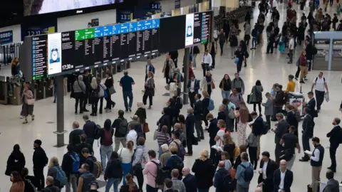 Getty Images A file image showing a crowd of passengers gathering on the concourse under arrival boards at Waterloo station, with most looking up to read times and destinations on the board