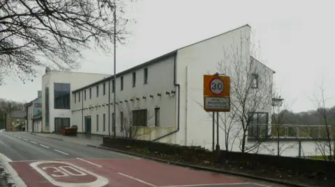 A building with a white exterior and a brown sign painted on the wall reads 'Casa'