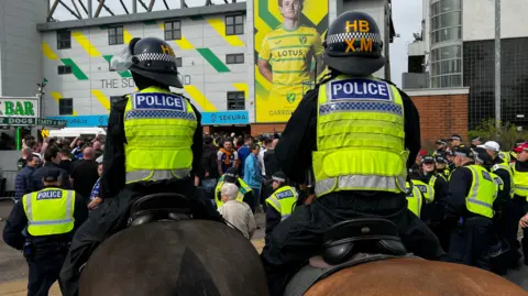 Police on horses and fans outside a football stadium