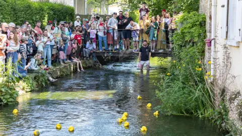 Dorset Bays Photography Yellow rubber ducks float around a river as crowds of people watch on