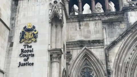 Brian Farmer/BBC A grey stone building with the words "Royal Courts of Justice" written in black on the side of a wall.