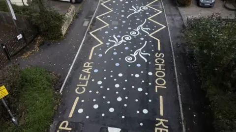 South West News Service A road with 'keep school free' markings on each side and dots and squiggles in between