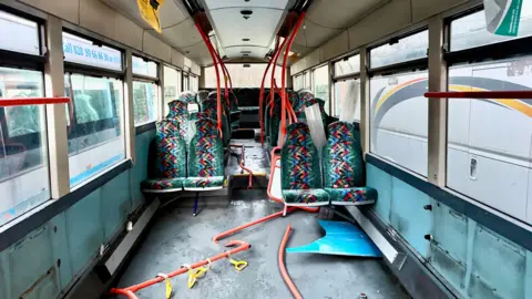 Luke Wilson The inside of a bus with parts ripped out.