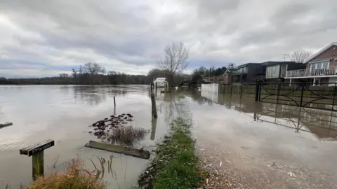 Homes on the right hand side of the picture, with the River Thames, which has broken its banks, flowing over the land 