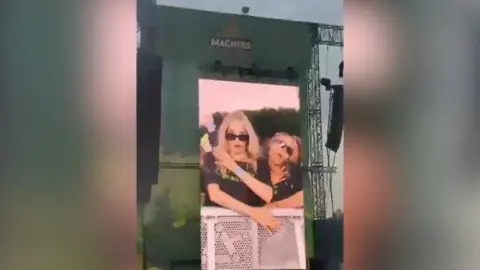 Jude Rooney Big screen at Belsonic. Two girls are pictured on it, dancing. They wear black tops.
