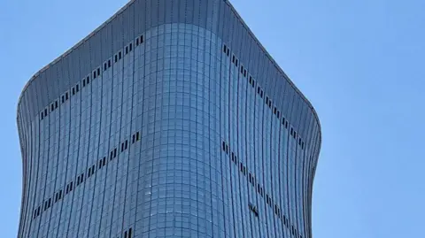 Side view of the top of CITIC tower in Beijing China, showing a hole where a small plane had crashed into