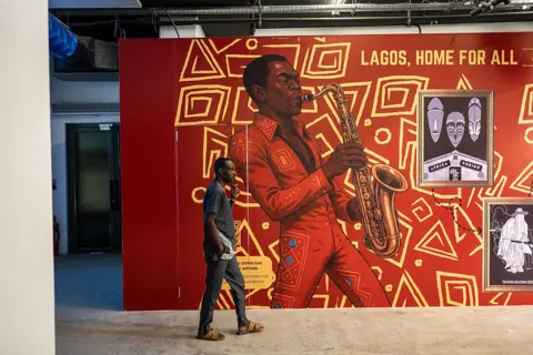 OLYMPIA DE MAISMONT / AFP / GETTY IMAGES A man walks past a painted wall depicting afrobeat pioneer Fela Kuti.