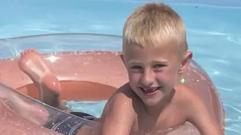 Family handout Freddie Farrow, who is blond, smiling and floating on an inflatable doughnut in a swimming pool.